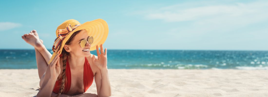 Woman enjoying her vacation by the sea tanning in the beach sand